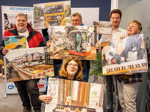 Einige Teilnehmer*innen präsentieren gemeinsam mit Jerome Major (2. von rechts) ihre auf Leinwände gedruckten Fotos