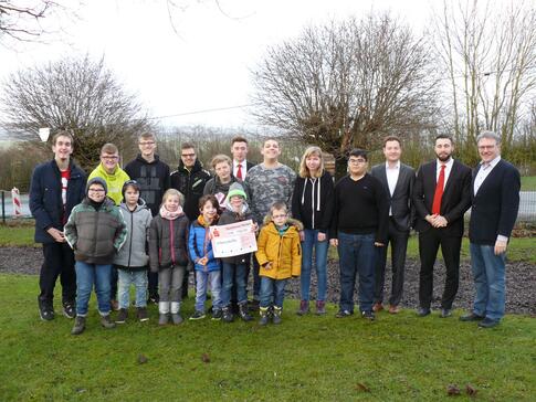 Übergabe der Spende an die Lebenshilfe - mit den Sparkassen-Auszubildenden Tobias Stuwe und Matthias Pankraz, dem Geschäftsführer der Lebenshilfe Brakel, Jerome Major, Schulleiter Alfred Kerlin und Schülern der von-Galen-Schule.