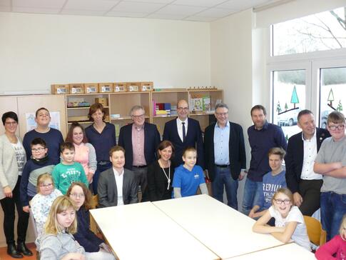 NRW-Schulministerin Yvonne Gebauer (Mitte, sitzend) mit dem Geschäftsführer der Lebenshilfe Brakel, Jerome Major (sitzend, neben Frau Gebauer), Schulleiter Alfred Kerlin (stehend, Vierter von rechts) sowie Schülerinnen und Schülern der von-Galen-Schule und weiteren Verantwortlichen der Lebenshilfe.